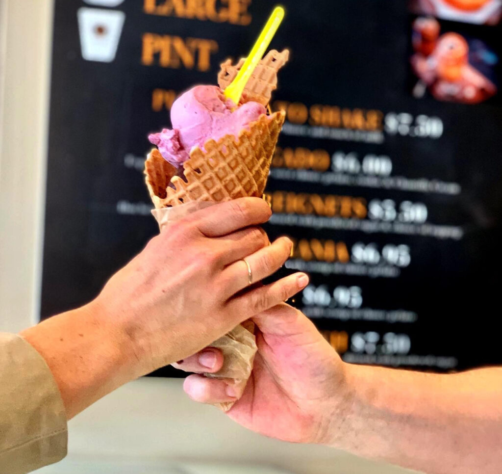Person handing ice cream in a cone to another person