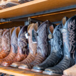 Display of cowboy boots in a variety of colors on shelf