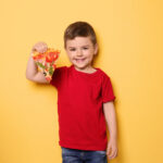 Little boy wearing red shirt and holding a pizza slice